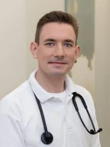 Dr. Jan Hendrik Knop mit weißem Hemd und Stethoskop um den Hals lächelt in die Kamera.